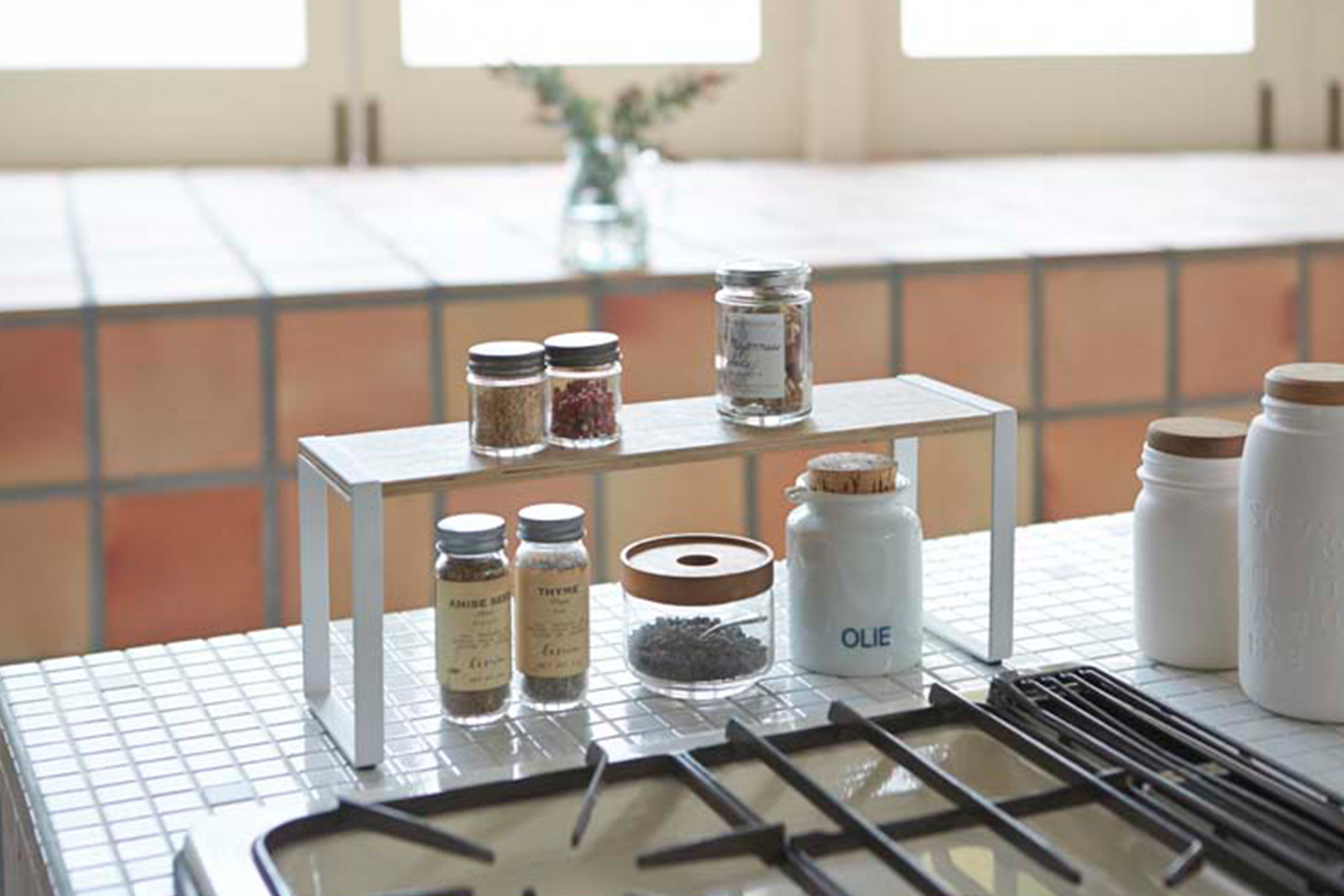 Spice jars on top of a White Wide Kitchen Rack riser next to the stove in the kitchen.