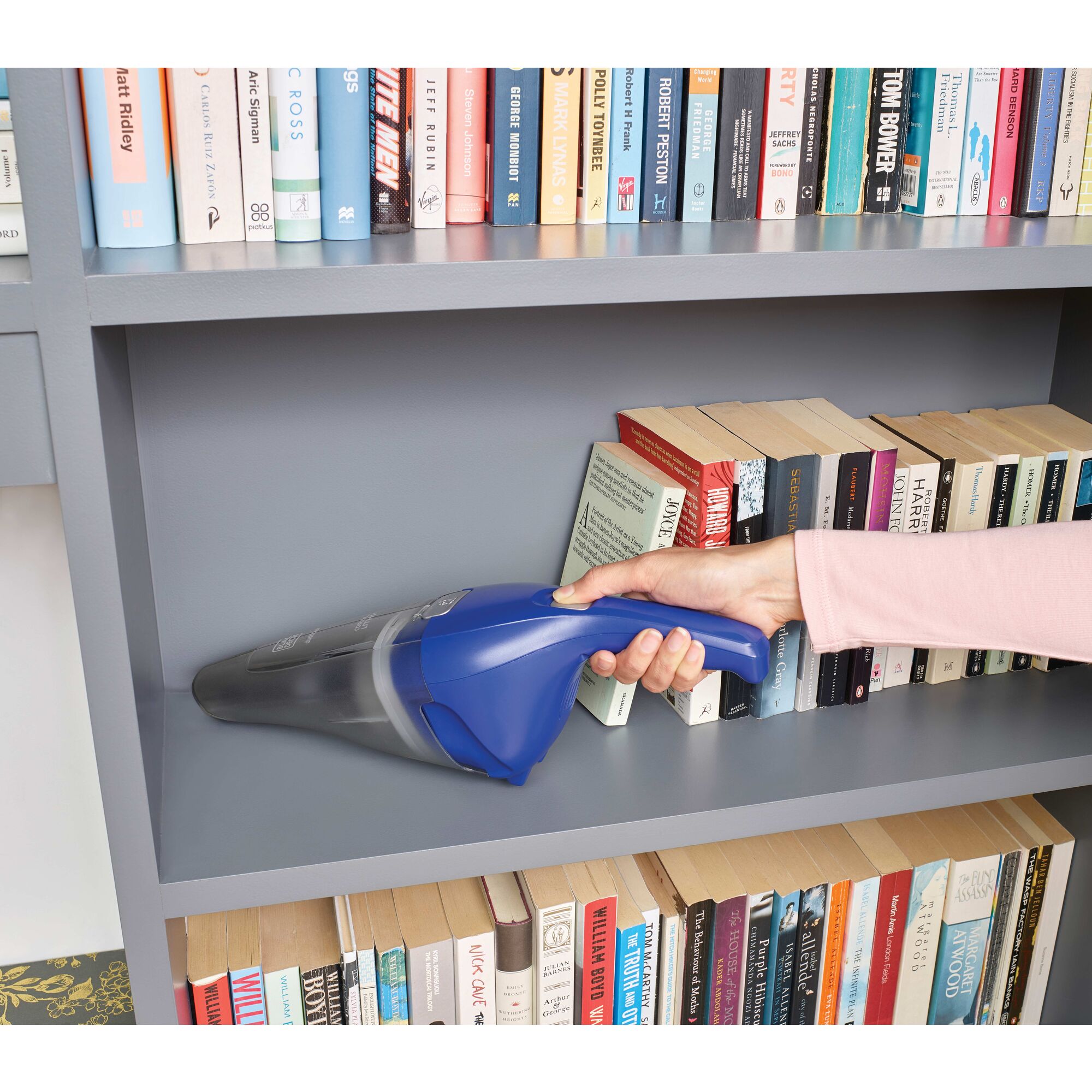 Dustbuster QuickClean Cordless Handheld Vacuum being used to remove dust from bookshelf.