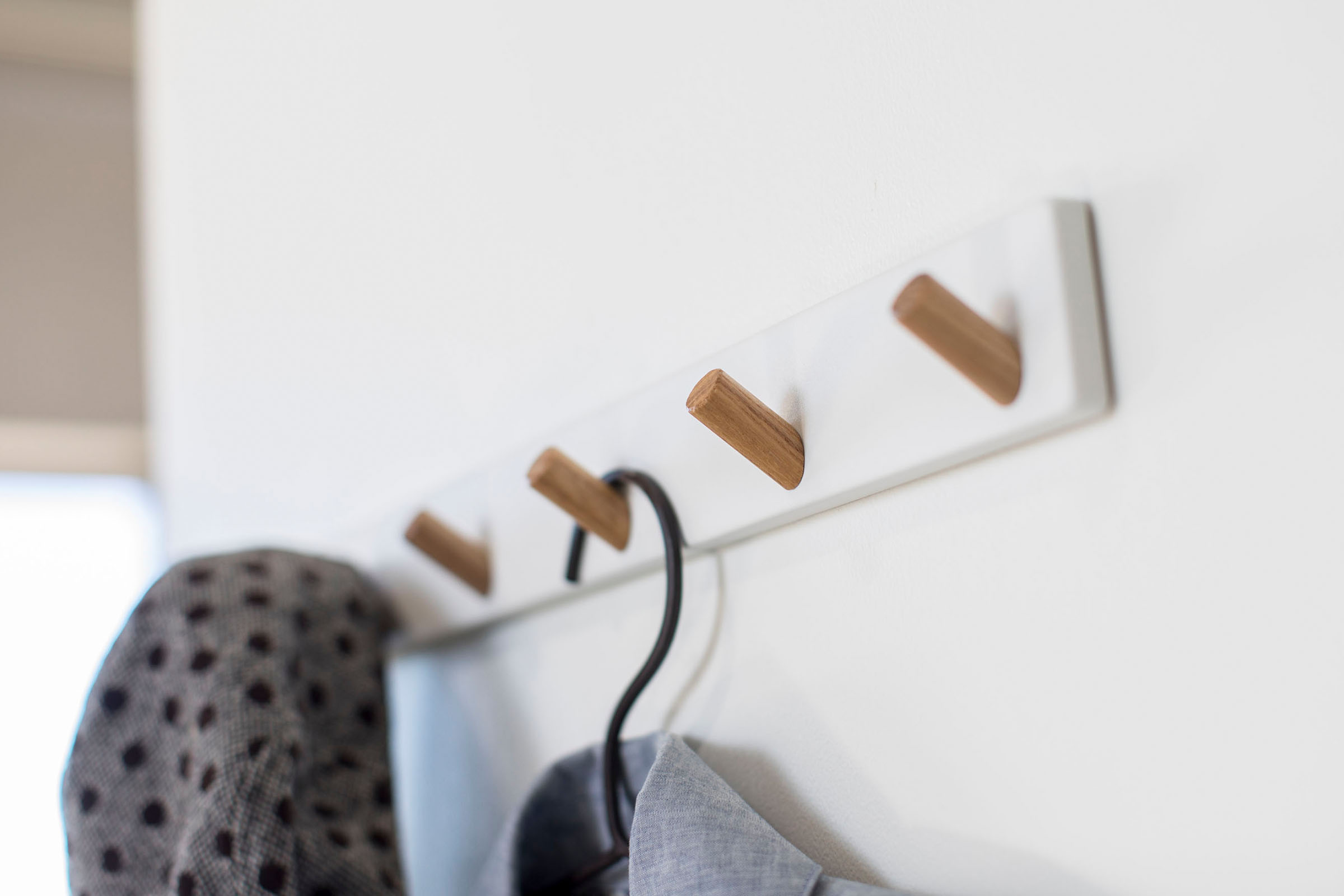 White Wall-Mounted Coat Hanger displaying coat and hat by Yamazaki Home.
