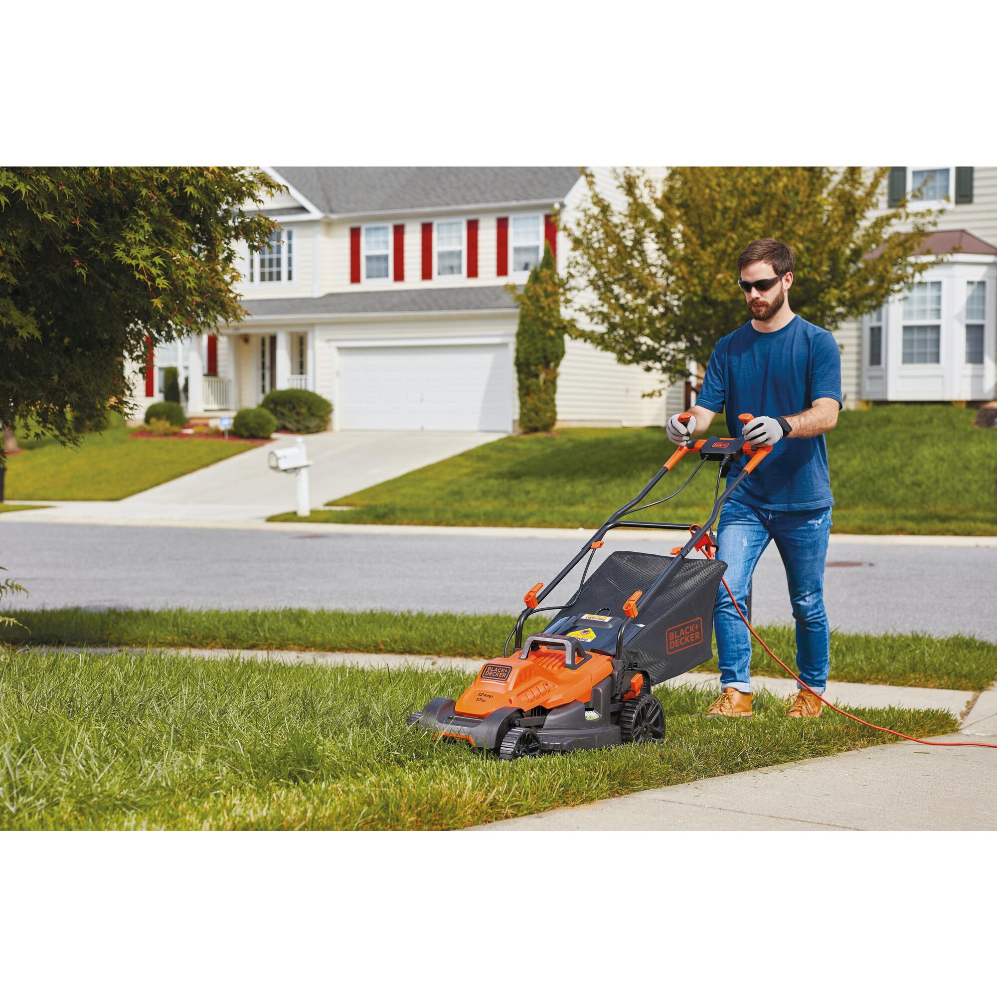 Black and decker 12 amp 17 inch electric lawn mower with comfort grip handle being used to cut grass.