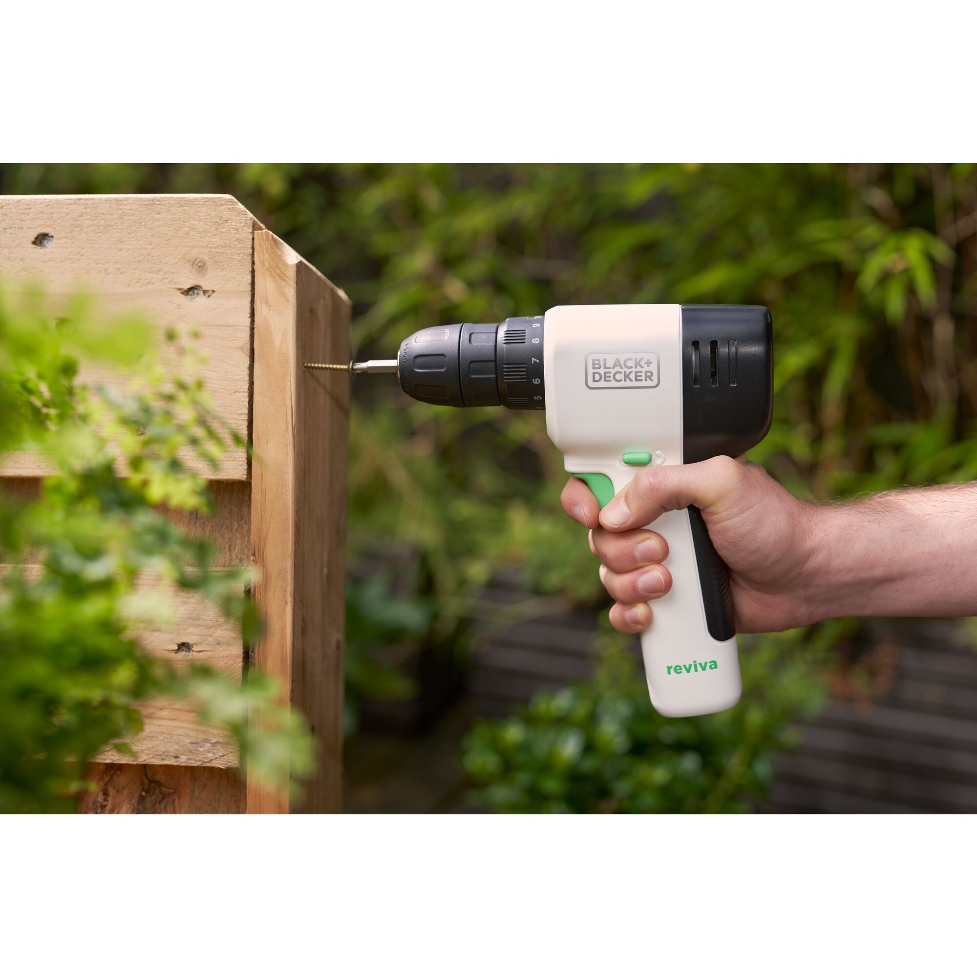 Hand using reviva™ 12V MAX* Cordless Drill/Driver to fasten a screw into a wood garden bed.