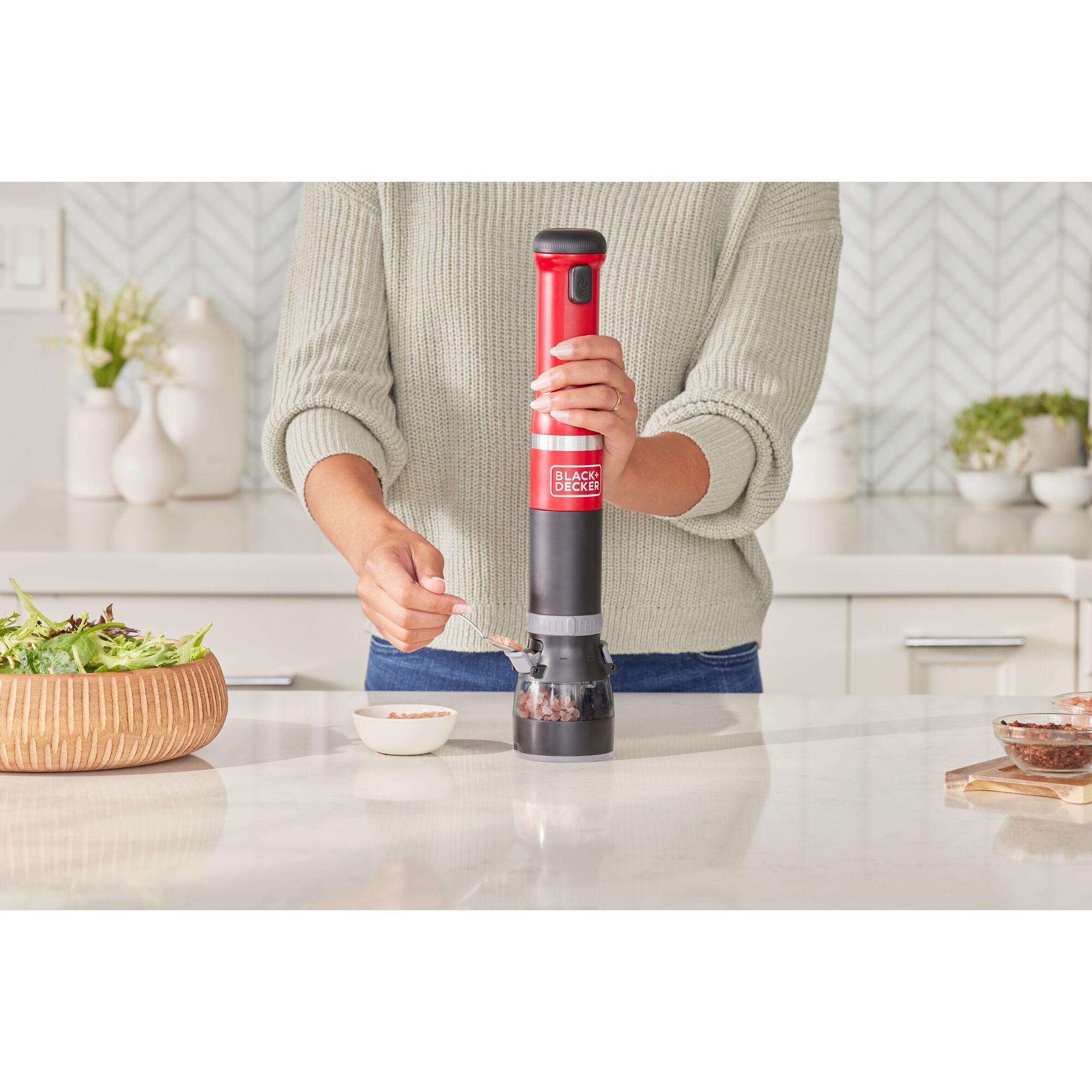 Talent adding salt crystals to the red BLACK+DECKER kitchen wand spice grinder attachment