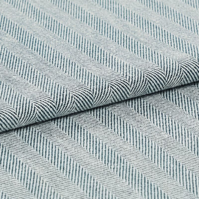 Folded woven textile with diagonal raised ribbed stripes in pale blue and white; fabric overlapped along a central fold; close-up view with soft, even lighting on a neutral surface.