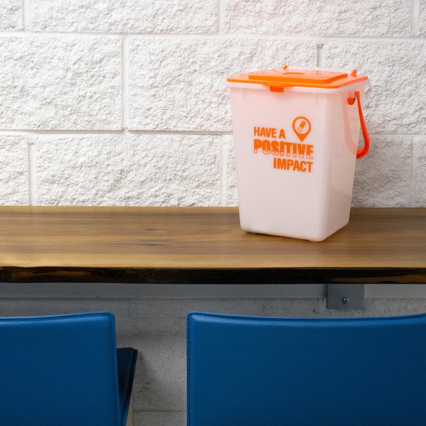 small container made from durable HDPE plastic with a white body and orange lid for collecting used batteries for proper recycling