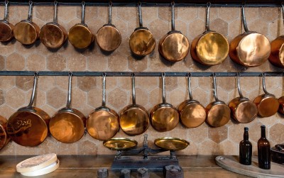 copper pots and pans hanging on a wall in a kitchen.