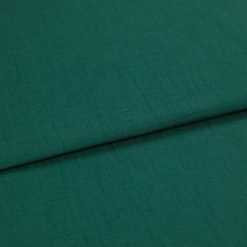 A folded teal-green woven fabric (linen texture) lies overlapping, the top edge forming a horizontal fold; close-up studio shot with even lighting and no visible background.