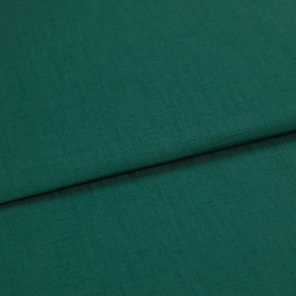 A folded teal-green woven fabric (linen texture) lies overlapping, the top edge forming a horizontal fold; close-up studio shot with even lighting and no visible background.