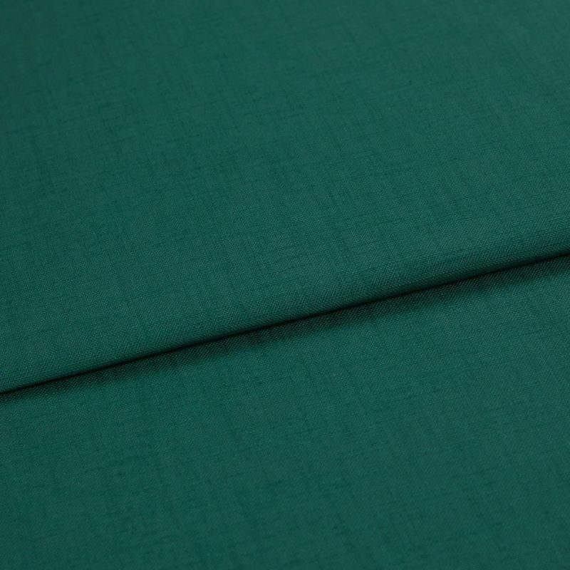 A folded teal-green woven fabric (linen texture) lies overlapping, the top edge forming a horizontal fold; close-up studio shot with even lighting and no visible background.