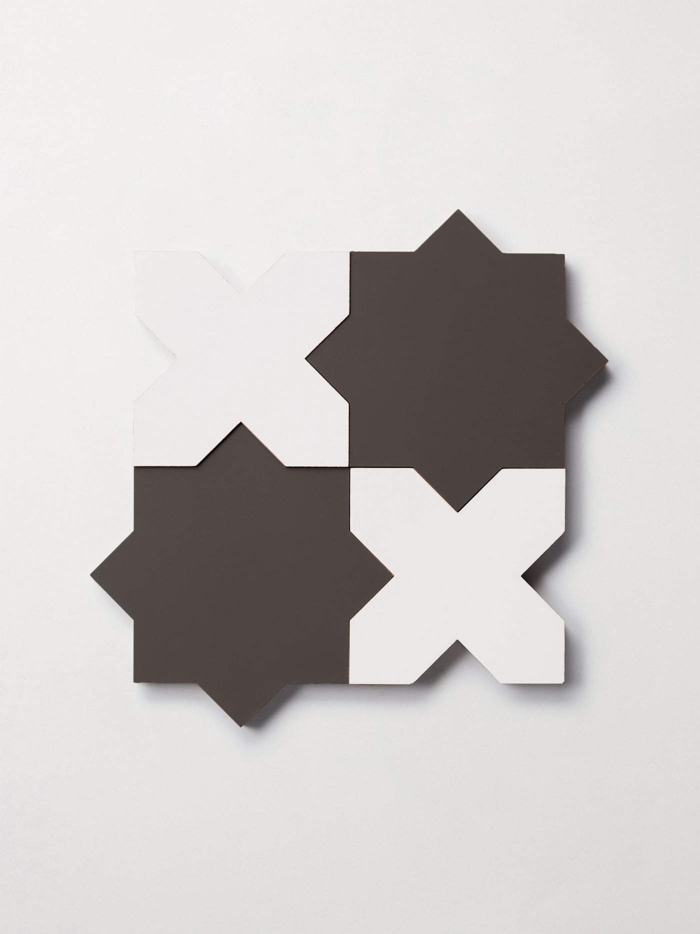 a set of black and white star and cross tiles on a white surface.