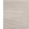 Beige cellular (honeycomb) blind, horizontal pleats with visible hexagonal cells at left edge; closed and diffusing light; photographed in a neutral, evenly lit studio setting with no visible room.