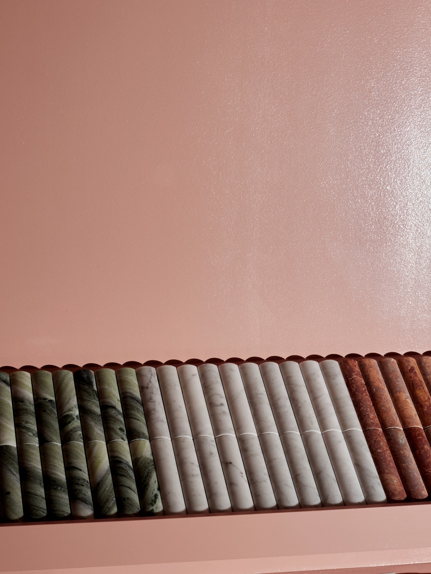 a row of marble tiles on a pink wall.