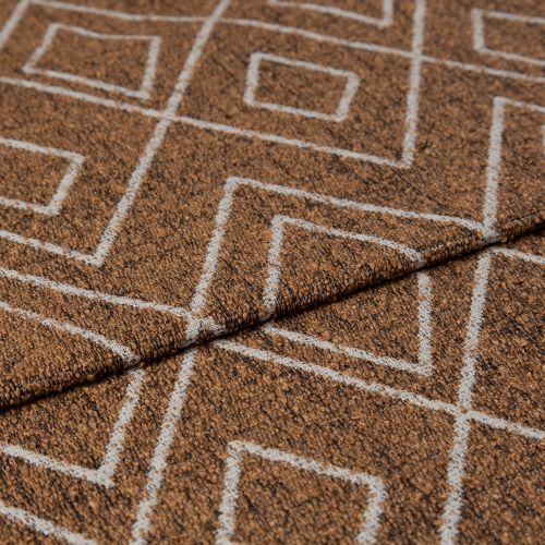 Brown looped-pile rug with white geometric square pattern, folded diagonally, edge overlapped showing stitched seam; close-up of textured surface under soft, neutral diffuse lighting.