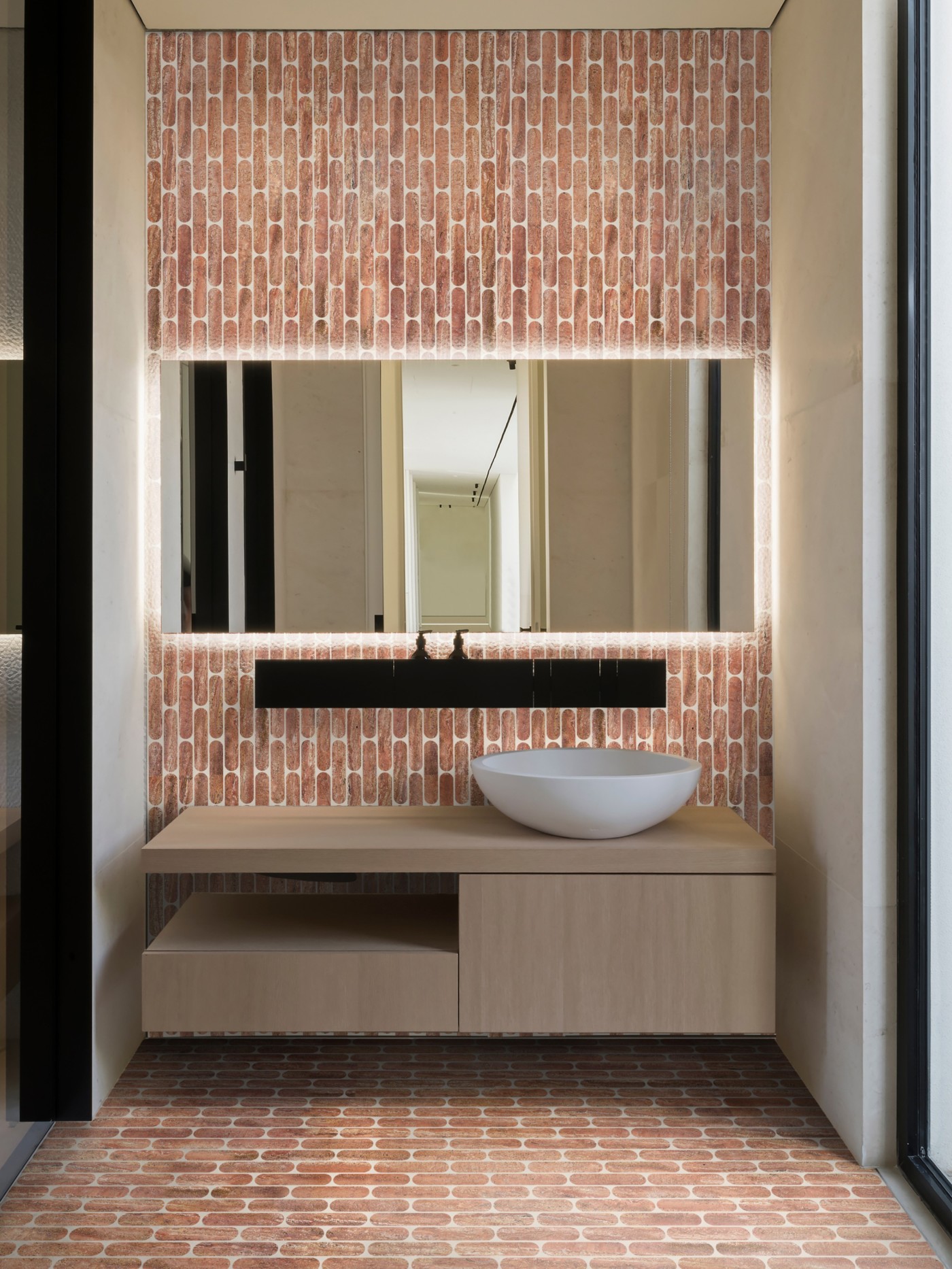 a modern bathroom with a brick tiled wall and floor.