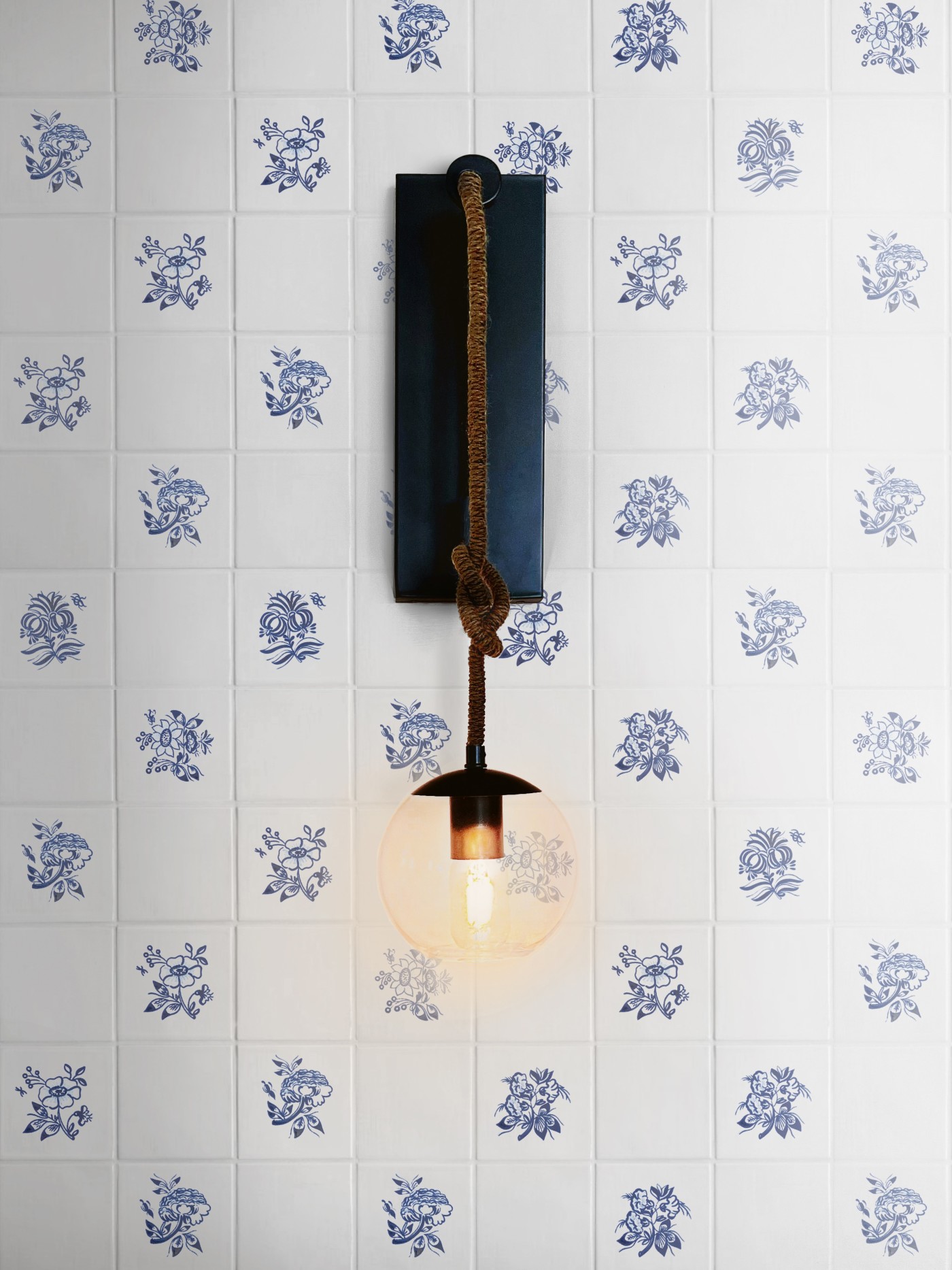 a light fixture on a wall with blue and white floral designs.