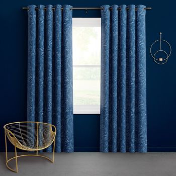 Blue grommet curtains, marbled swirl, hung on a rod and parted to frame a central window; filtering daylight; dark-blue room with a gold wire chair and circular wall décor.