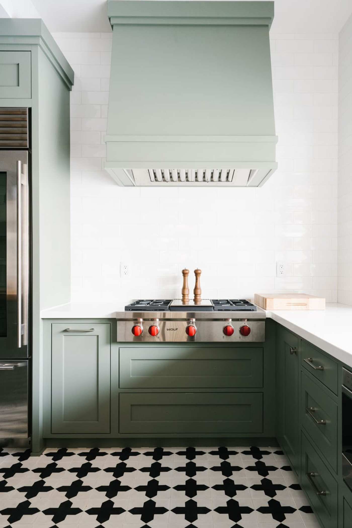 a kitchen with green cabinets and a black and white patterned floor.