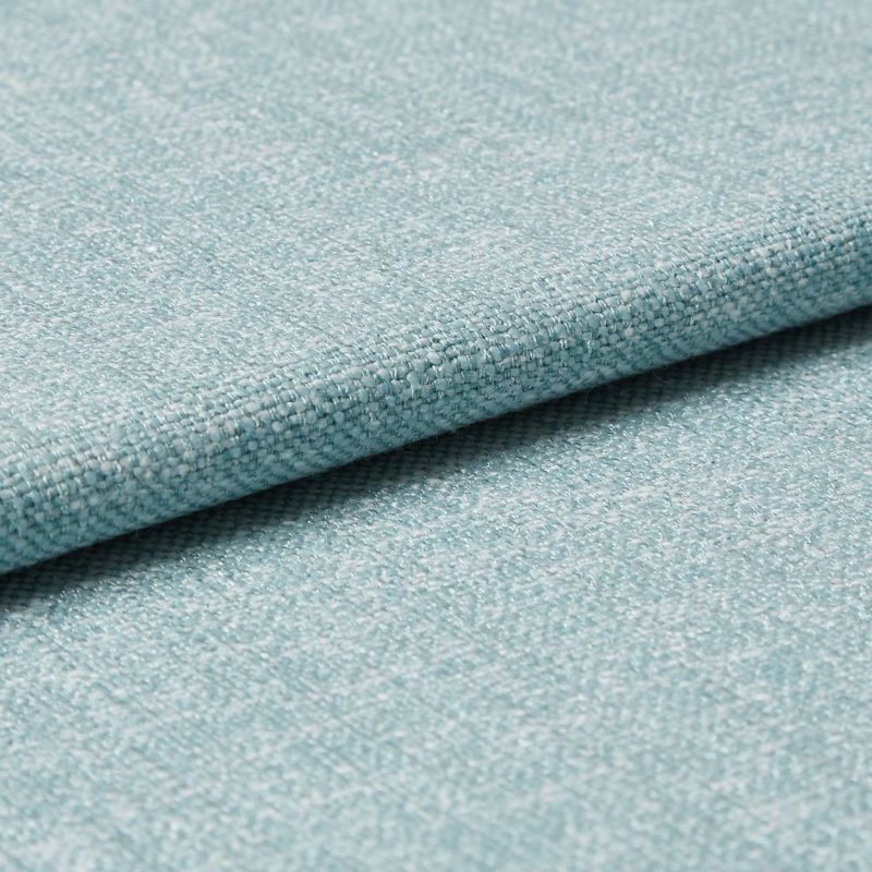 Light-blue woven upholstery fabric folded so one edge overlaps, revealing tight textured weave; photographed as a close-up on a flat surface with soft, even studio lighting for a material sample.