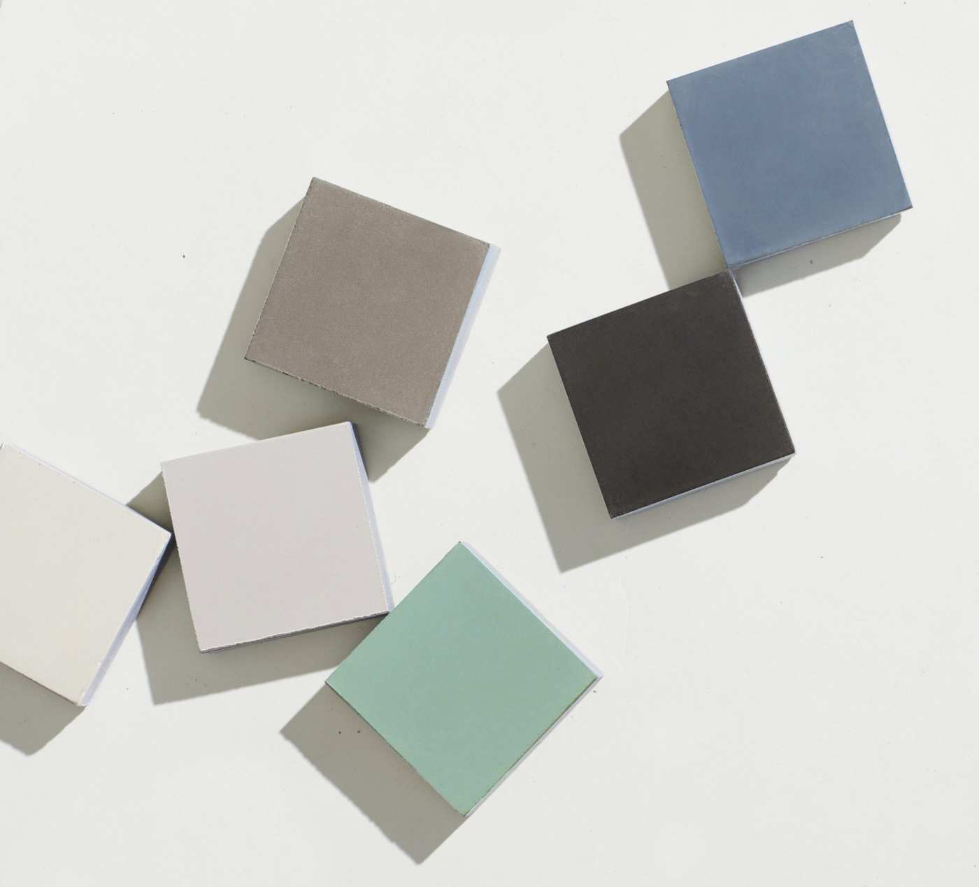 five different colored square tiles arranged on a white surface.