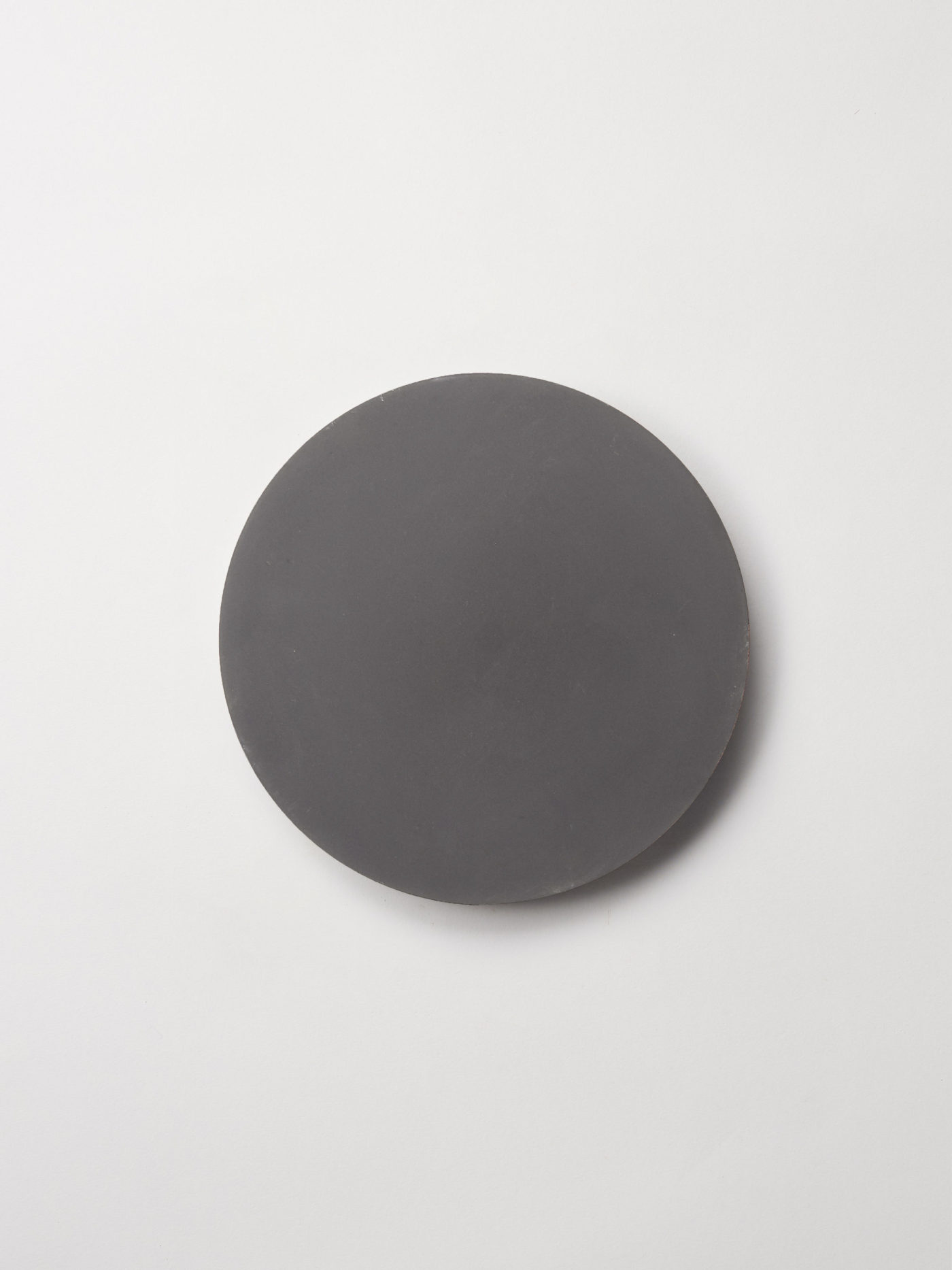 a circular black tile on a white surface.