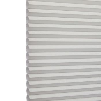 White cellular (honeycomb) blind, left-edge visible with uniform horizontal pleats; fully lowered and closed, softly filtering daylight; set against a bright, neutral interior background.