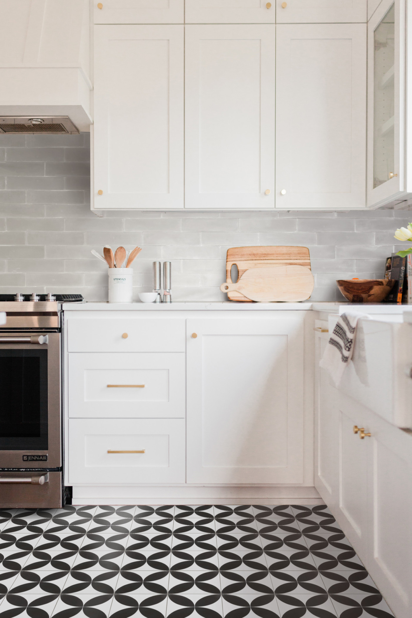 a kitchen with a black and white tiled floor and white cabinets.