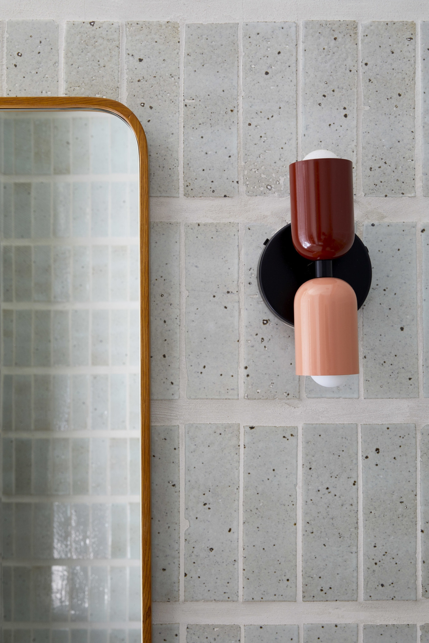 a bathroom with a grey tiled wall and a mirror.