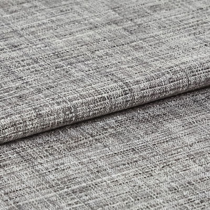 Woven grey curtain fabric folded into overlapping horizontal layers, showing coarse, irregular weave; tight close-up with neutral lighting highlighting texture and subtle tonal variation.