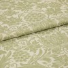 Green-and-cream floral-patterned fabric, folded with an overlapping edge, displaying woven texture and grape-and-leaf motifs; close-up studio shot with soft, even lighting suggesting an upholstery or curtain sample.
