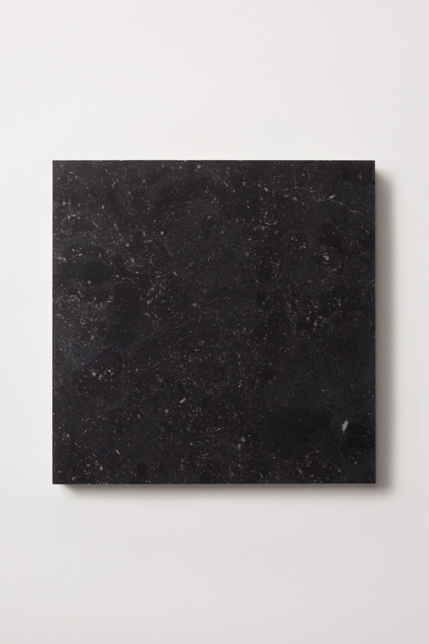 a square black limestone tile on a white surface.