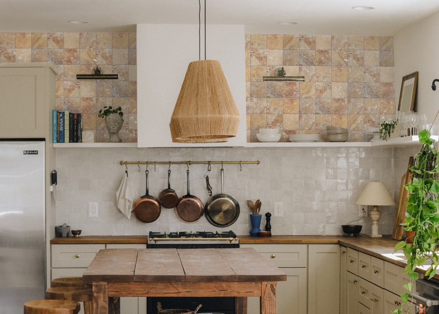 a kitchen with a table and a hanging lamp and hanging pots.