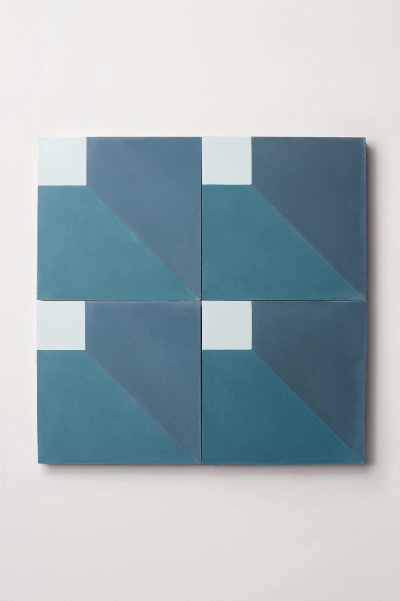 four blue and white patterned tiles on a white background.