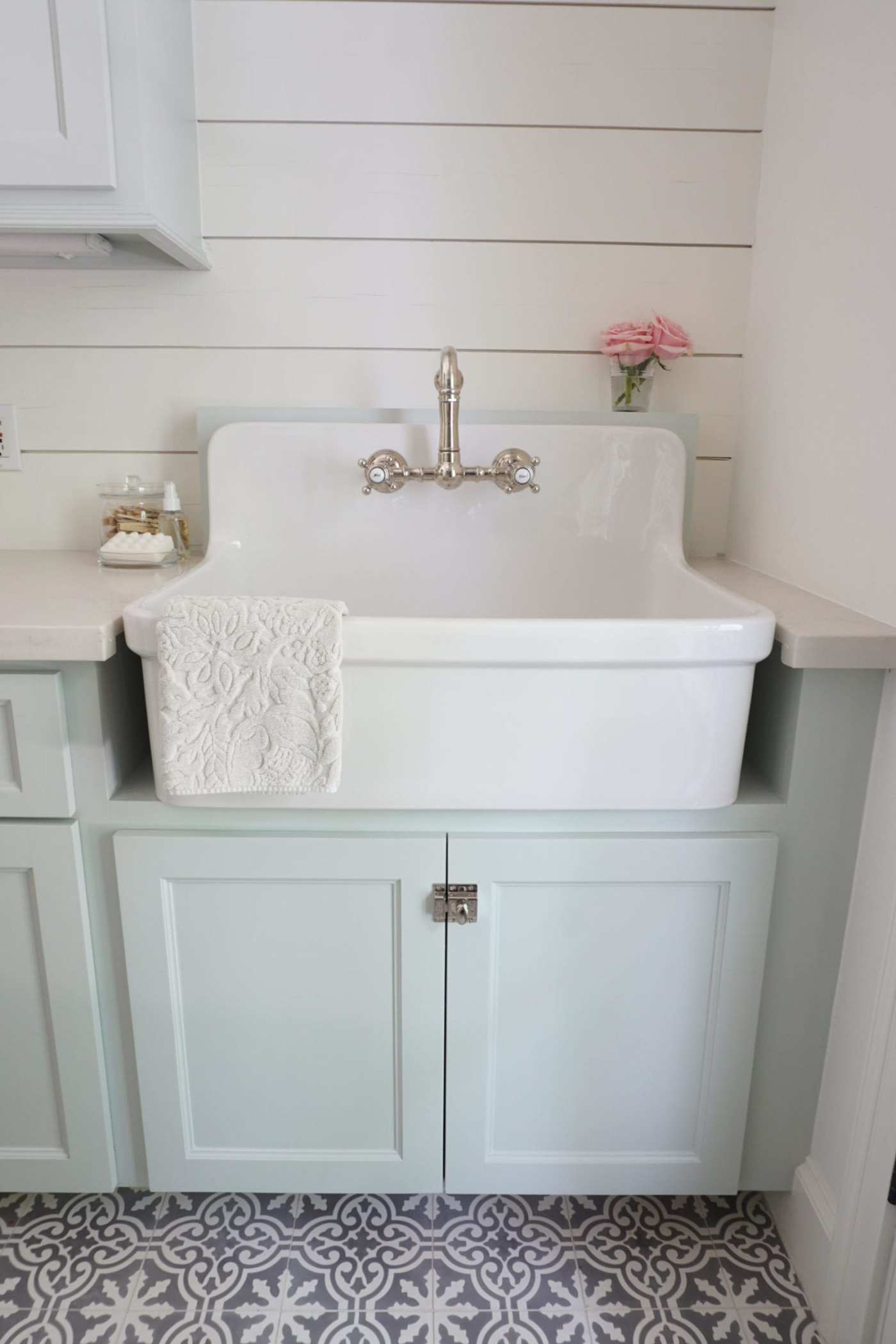 a white kitchen with a sink above light blue cabinets and a blue and white tiled floor.