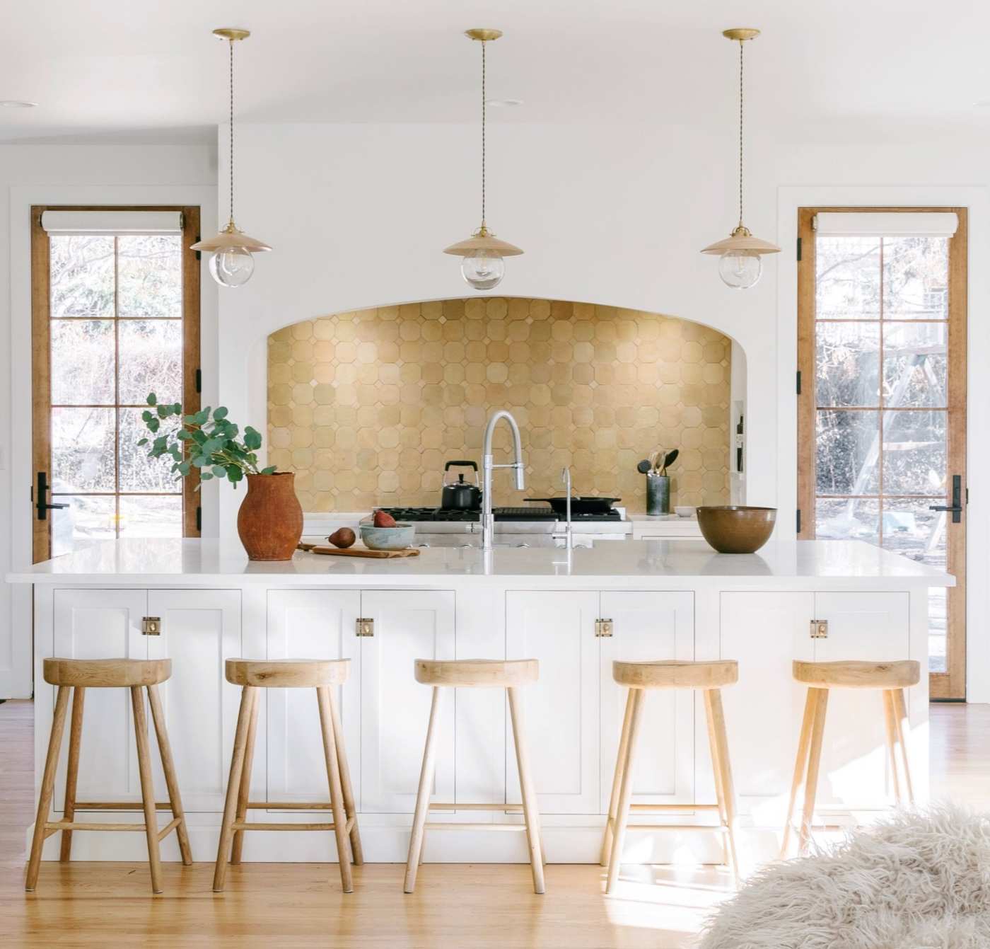 a white kitchen with a wooden island and stools.