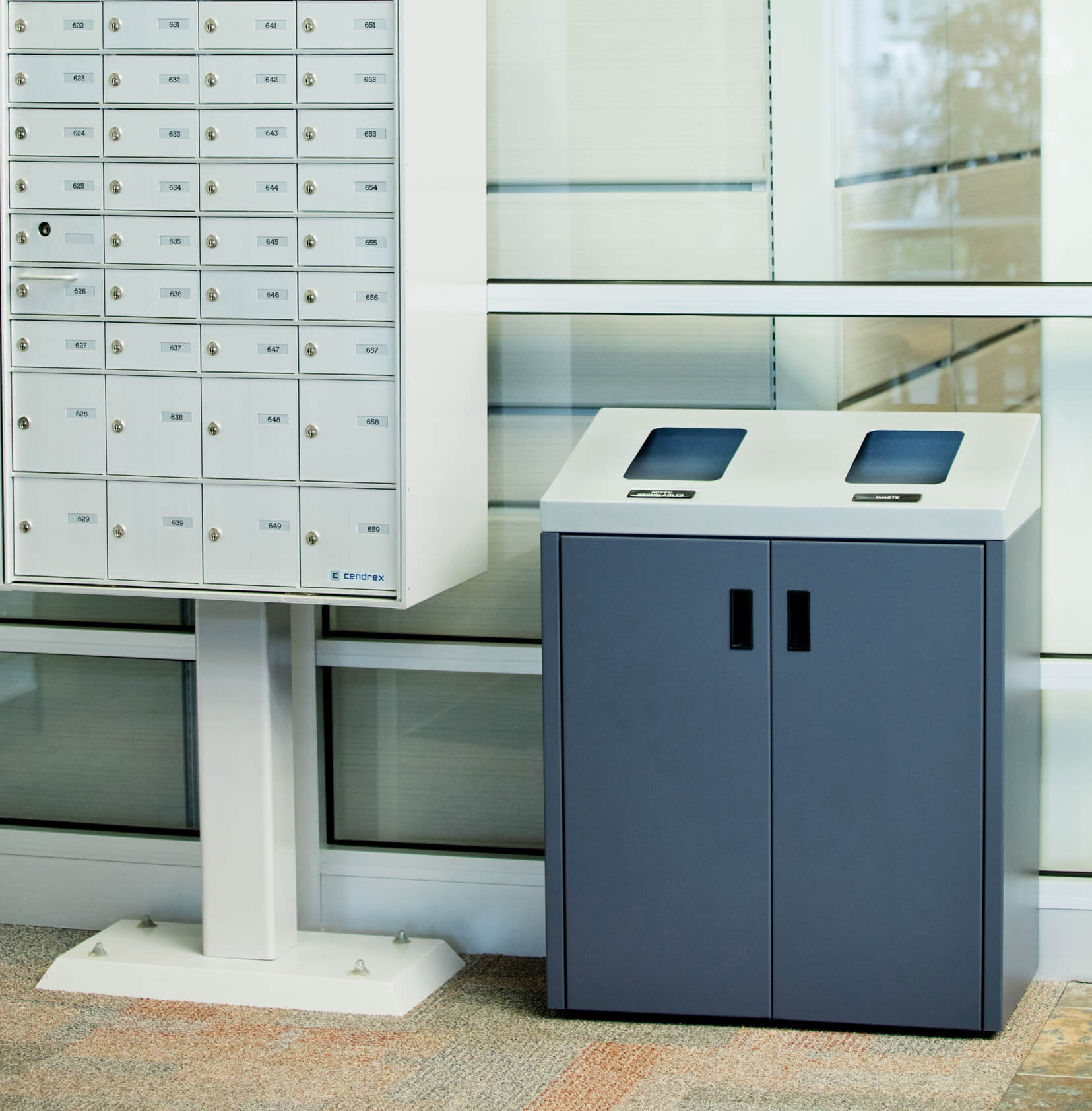 double stream trash and recyclables bin in the entrance of a corporate office sitting beside a mail box