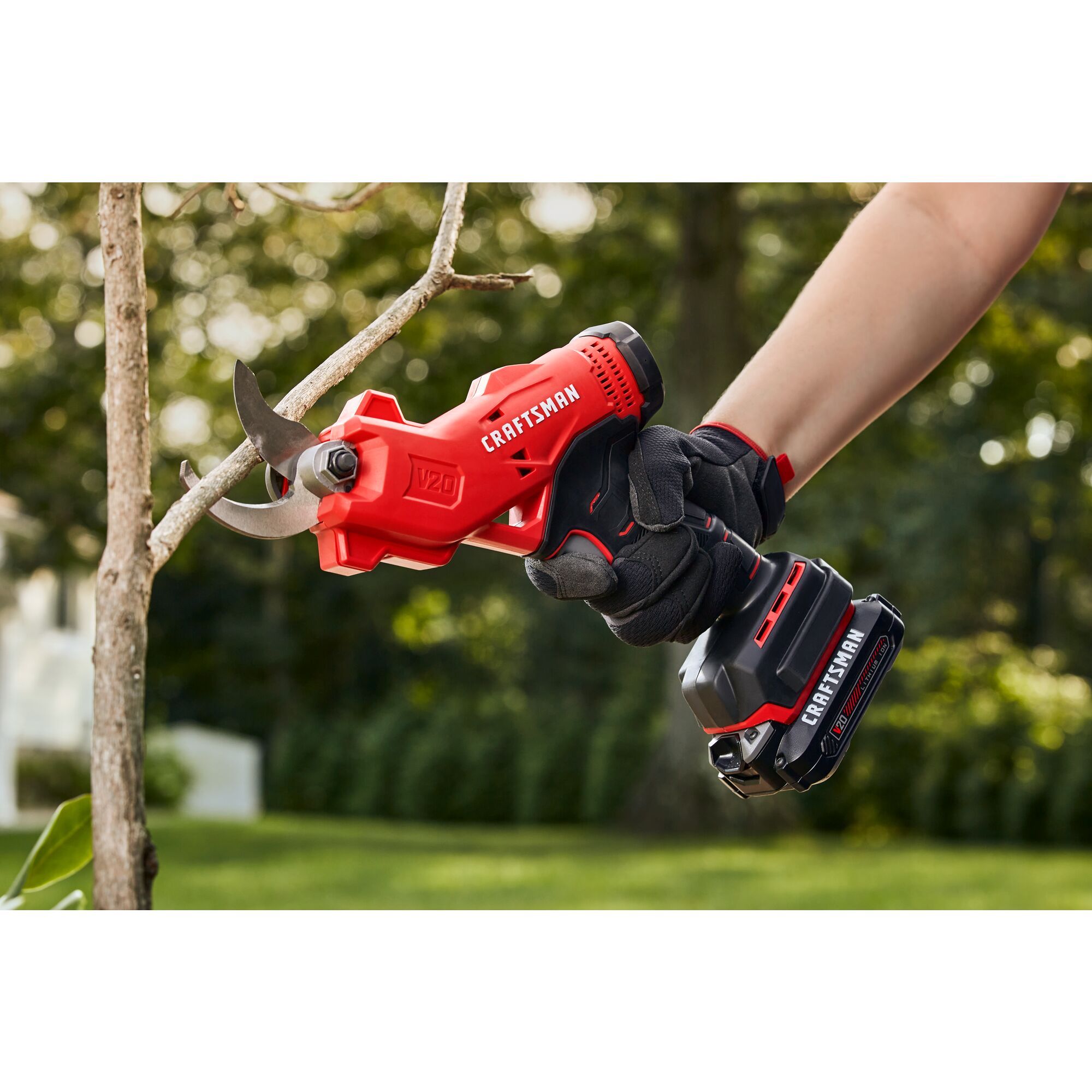 20 volt cordless pruner kit being used by a person to cut a branch in the garden.