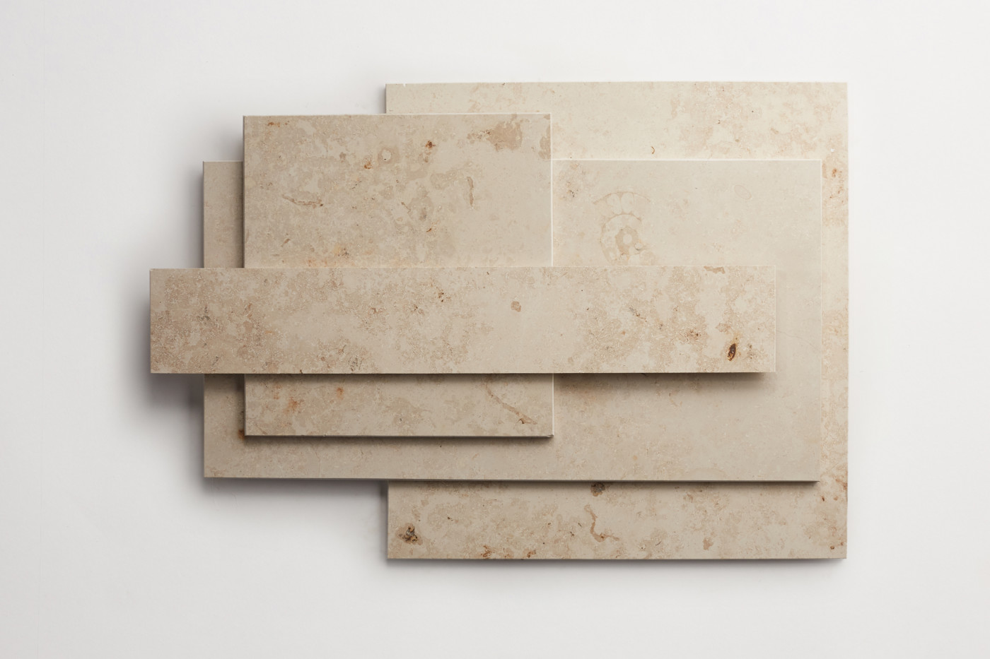 a stack of various sized limestone tiles on a white surface.