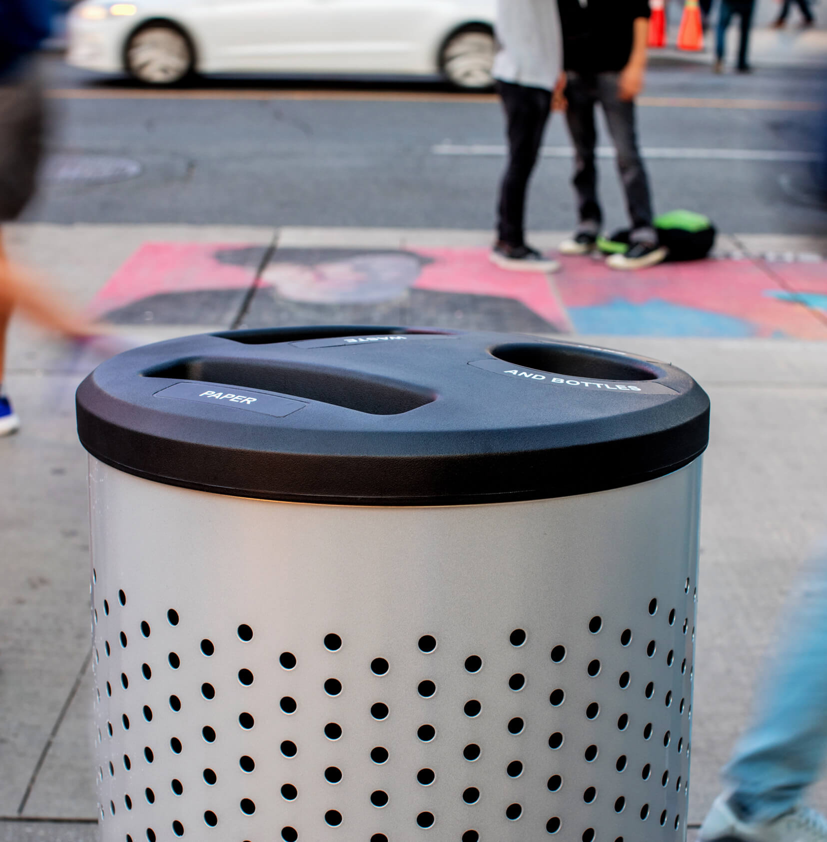 closeup of a metal and plastic multi-stream waste and recycling container outside on a busy city sidewalk