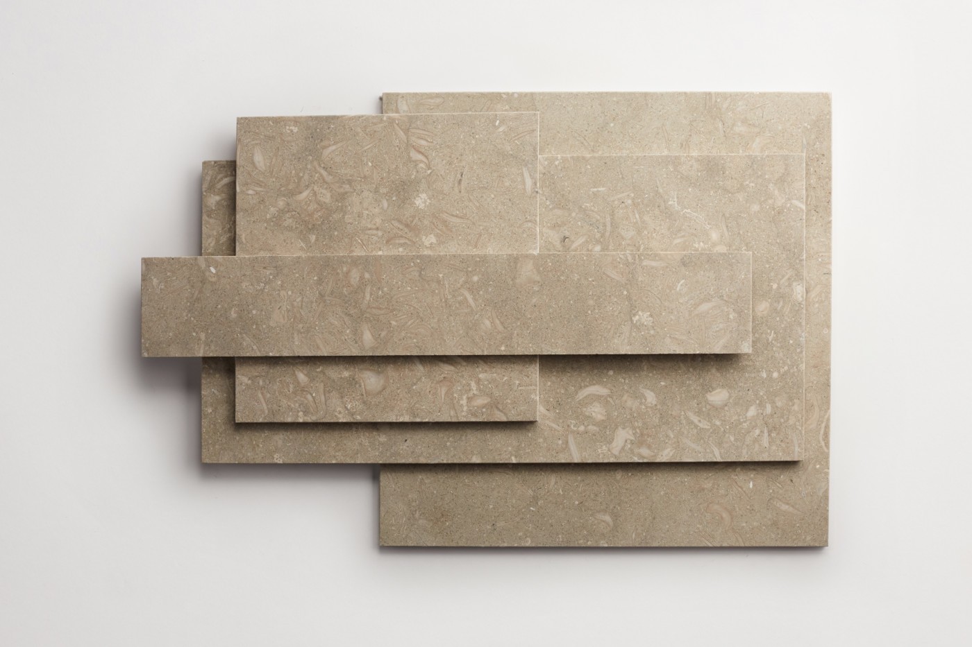 a stack of various sized limestone tiles on a white surface.