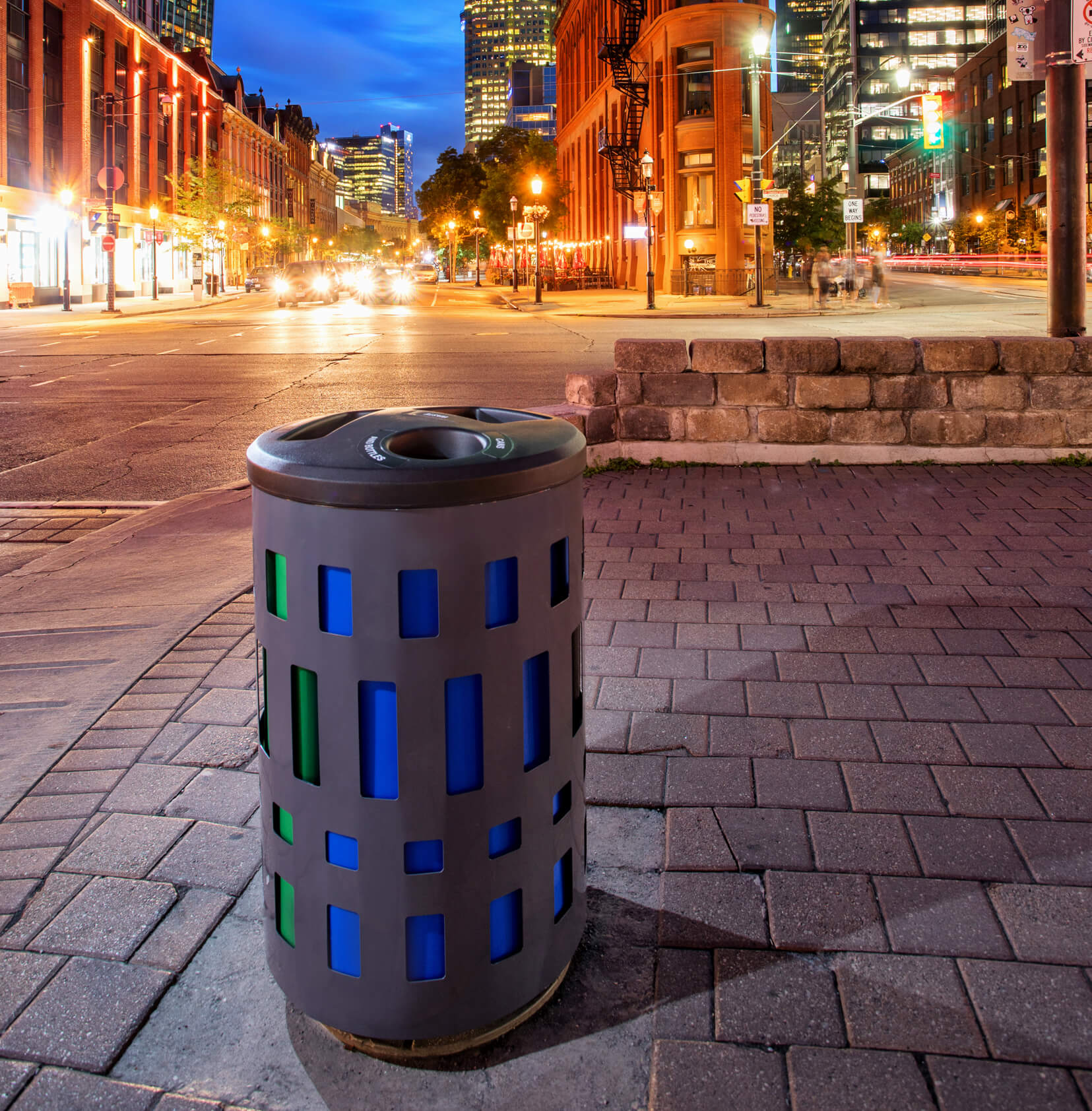 triple recycling and trash container made from durable powder coated steel with plastic lid and color-coded liners streetside on a city sidewalk