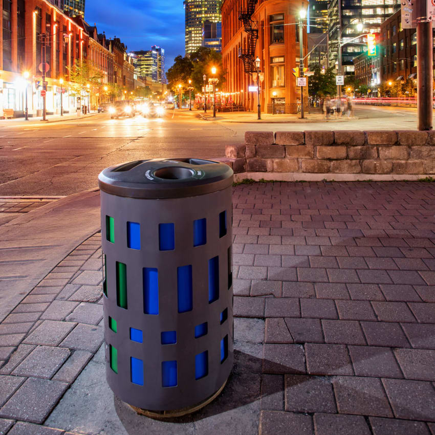 triple recycling and trash container made from durable powder coated steel with plastic lid and color-coded liners streetside on a city sidewalk