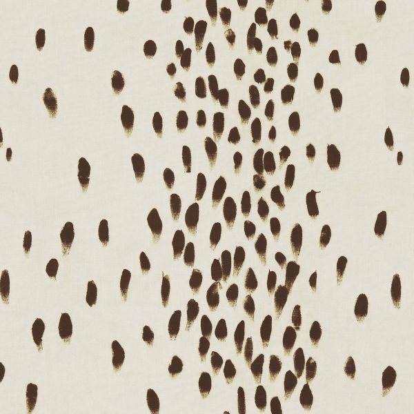 Cream fabric patterned with irregular brown brushstroke ovals — clustered centrally and scattered outward — covering a flat surface under even, neutral lighting, resembling abstract textile or wallpaper.