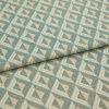 Woven geometric upholstery fabric, teal and beige diamond-triangle pattern, folded once across center, showing textured weave and repeating motifs; close-up, neutral soft lighting, studio-style flat lay.