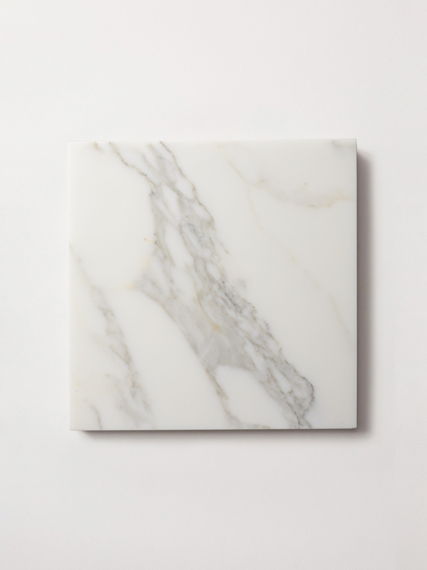 a square white marble tile on a white surface.