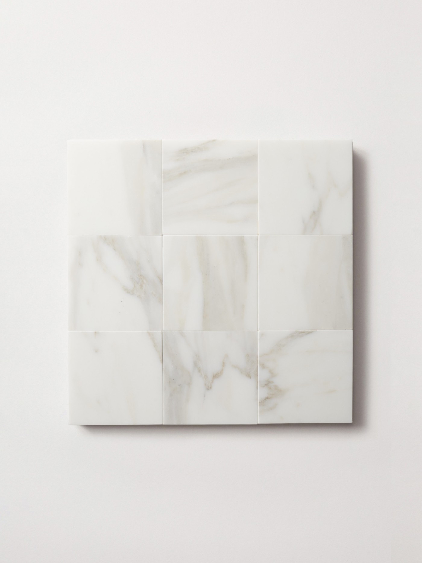 a set of square white marble tiles on a white surface.