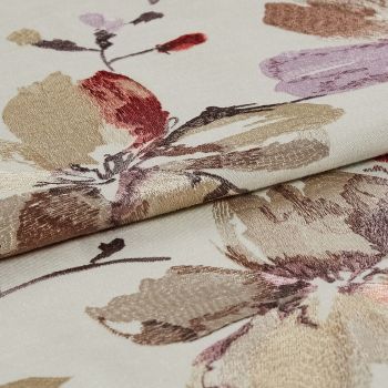 Folded cream jacquard fabric with metallic beige, mauve and red floral motifs — layered to reveal raised sheen and woven texture — close-up on flat surface under soft, even lighting.