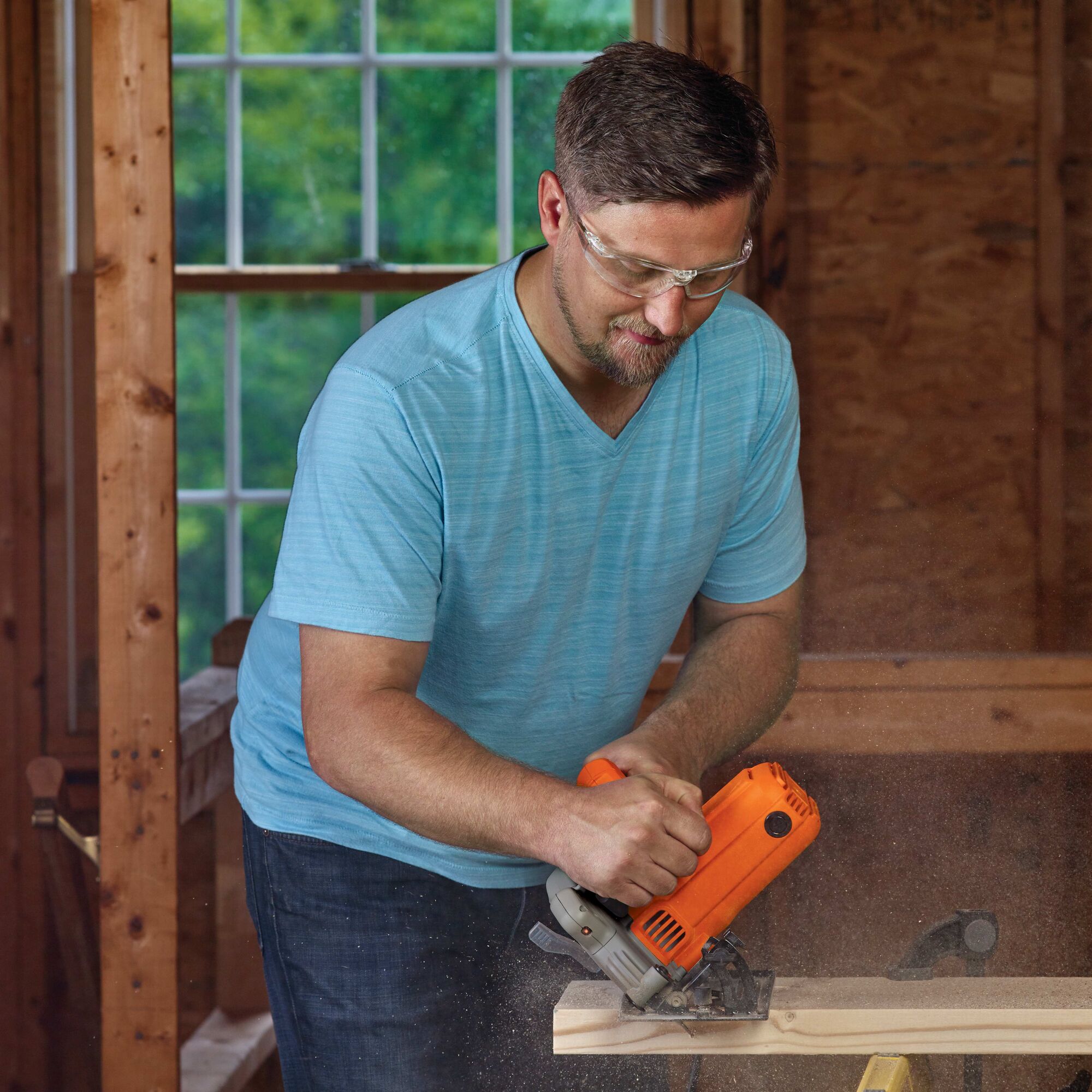 Man wearing safety goggles using the bevel feature of the circular saw