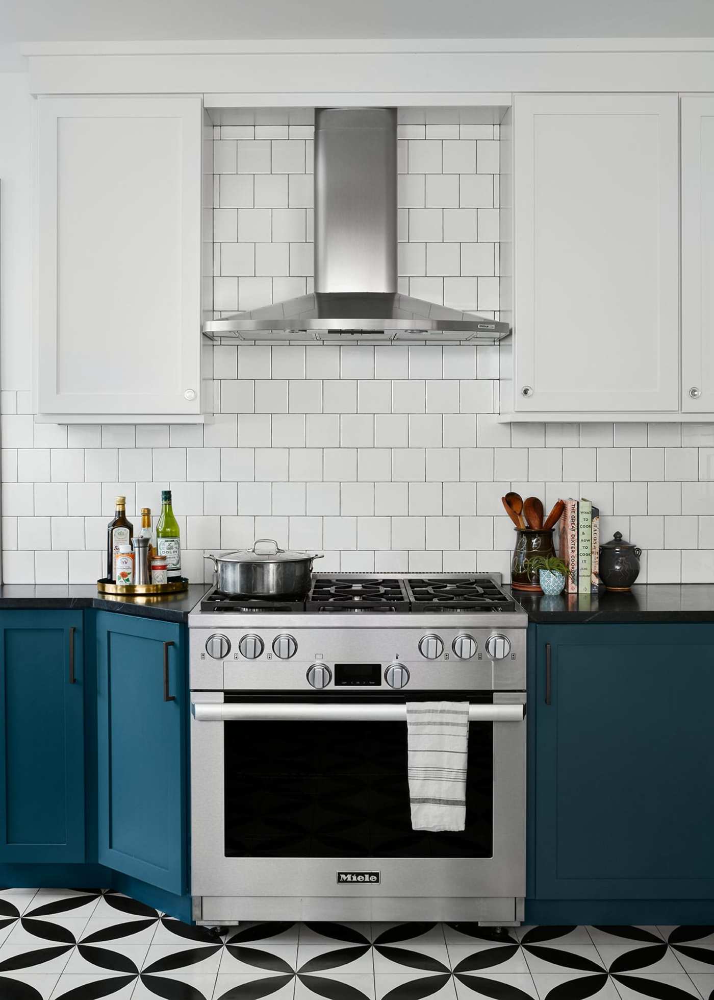 a kitchen with blue cabinets and black and white patterned floors.