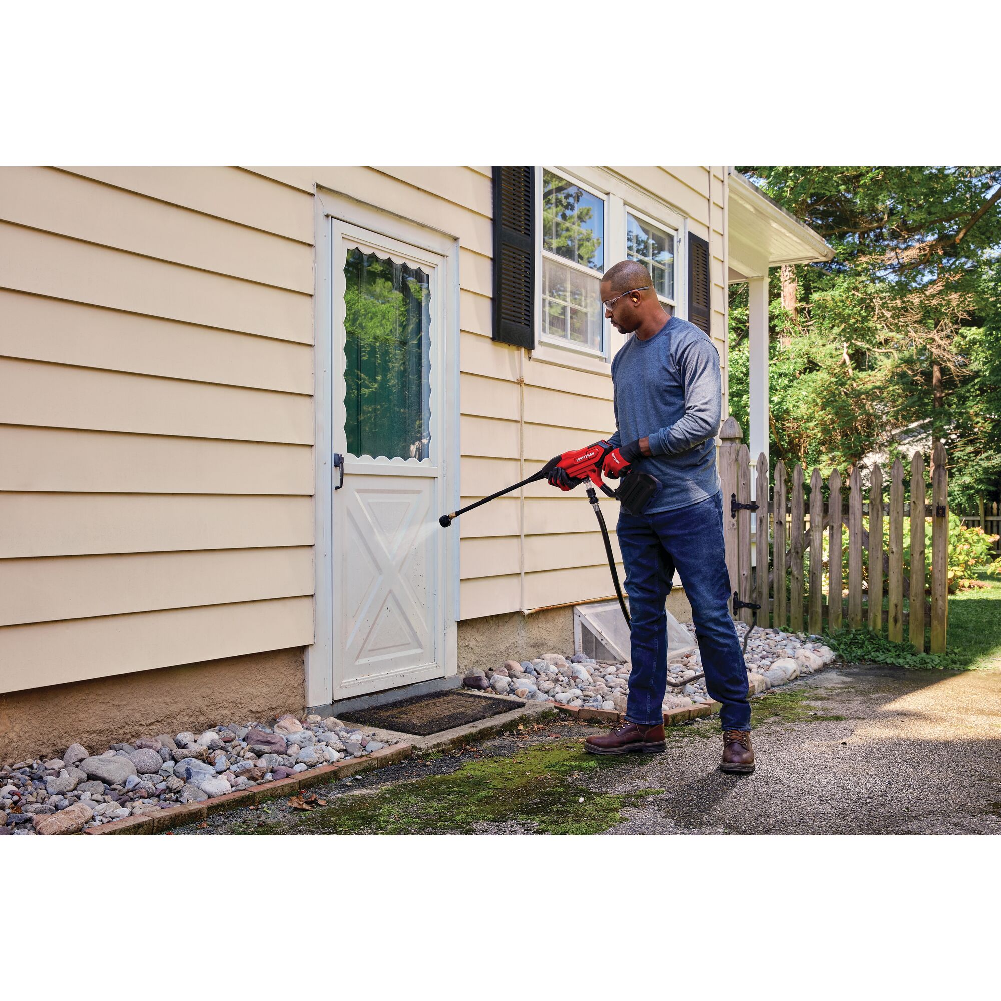 20 volt cordless 350 max P S I power cleaner kit being used by a person to clean a door outside.