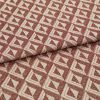 Woven upholstery fabric with repeating terracotta-and-cream triangular motif, folded once across the frame, revealing textured weave and raised pattern; close-up, evenly lit studio shot on neutral surface.