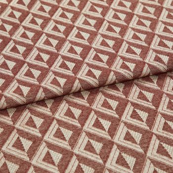 Woven upholstery fabric with repeating terracotta-and-cream triangular motif, folded once across the frame, revealing textured weave and raised pattern; close-up, evenly lit studio shot on neutral surface.